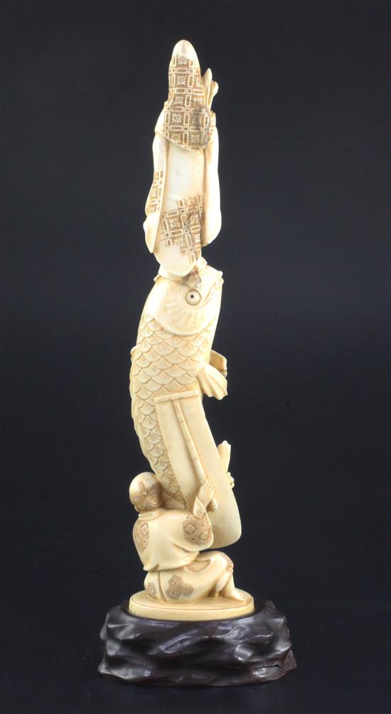 A Japanese ivory okimono of Kwannon standing upon a giant carp, early 20th century, 24.3cm, wood stand